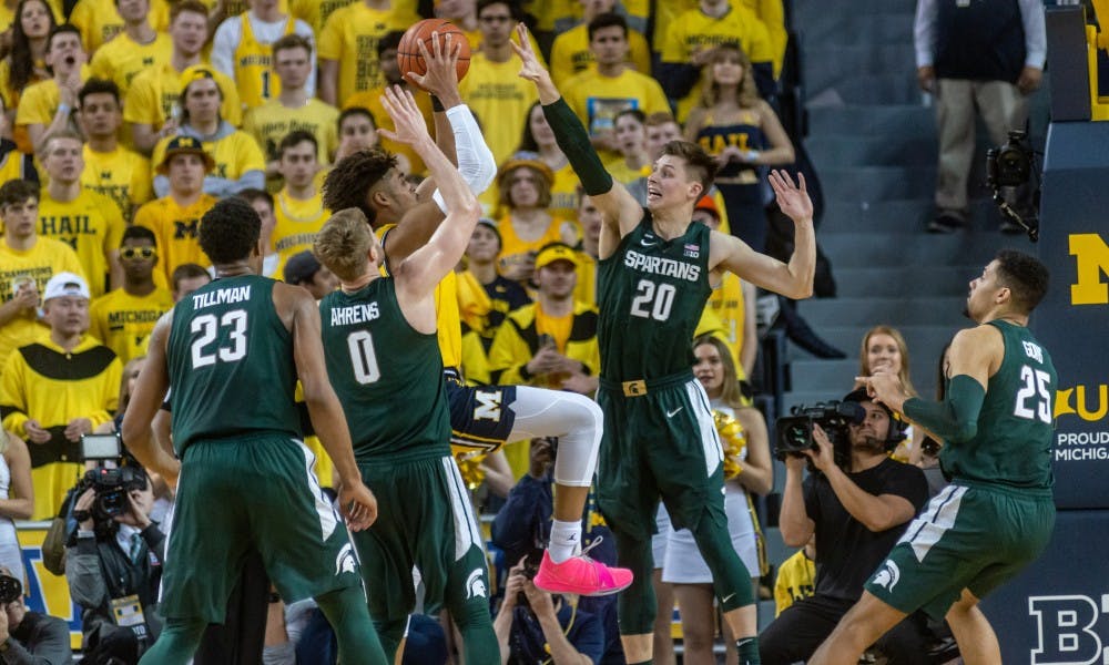 <p>Senior guard Matt McQuaid (20) defends a shot from Michigan's Jordan Poole. The Spartans beat the Wolverines, 77-70, Feb. 24, 2019 at the Crisler Center.</p>