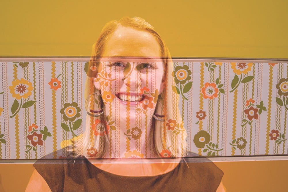 <p>Studio art masters student Laura Baszynski poses for a portrait in this double exposure, with her artwork at the MFA Broad Exhibition reception on April 7, 2018 at the Broad Art Museum.&nbsp;</p>
