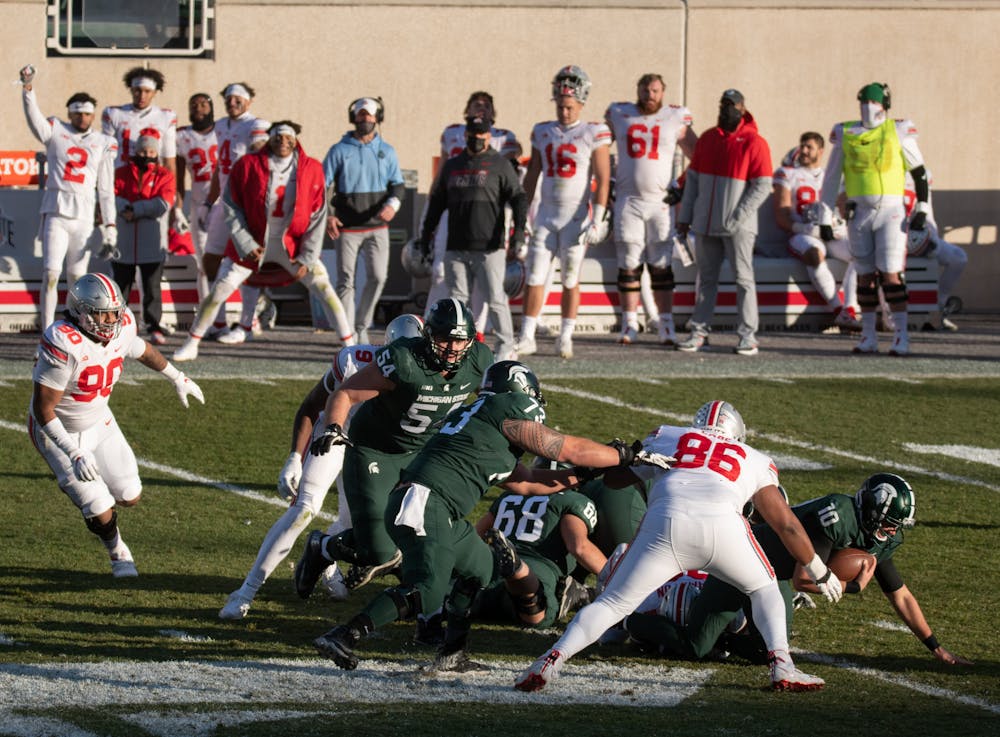 <p>MSU quarterback Payton Thorne (10) gets tackled by Ohio State defenders in a game on Dec. 5, 2020.</p>