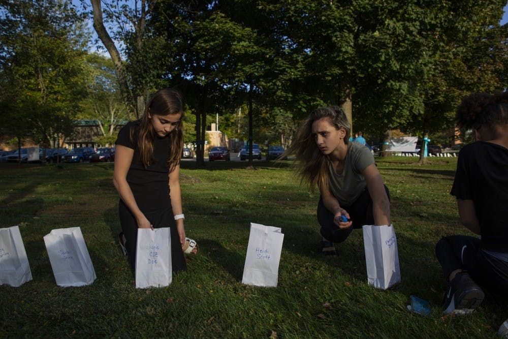 Lilia Cosman, 12 and her sister Amanda, 14, who’s also a survivor light candles on Oct. 10, 2019 at the East Lansing Public Library. POSSE lit 505 luminaries signifying the known survivors Larry Nassar at the East Lansing Public Library, before President Stanley’s meeting with survivors. 
