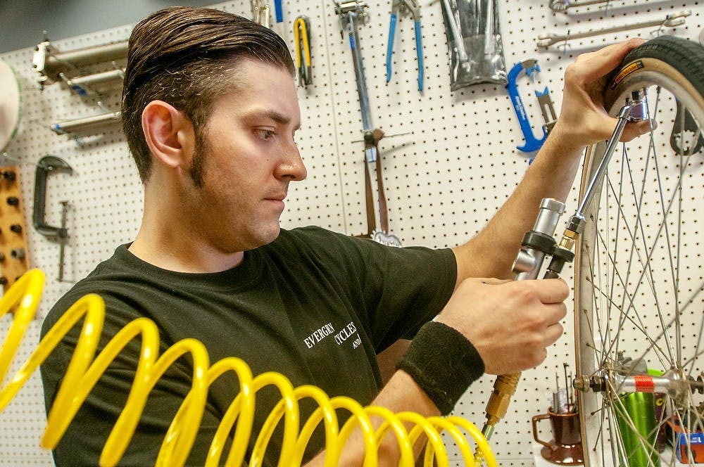 	<p>Evergreen Cycles and Repair store manager Justin Miernik puts air in a tire July 8,2013 at Evergreen Cycles and Repair store, 545 E. Grand River. Miernik said the store works on about five to ten bikes a day. Weston Brooks/The State News</p>