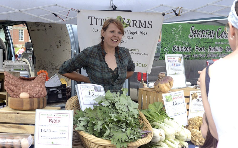 <p>MSU alumna Rebecca Titus helps out a helps out a customer at this year's East Lansing Farmer's Market June 6th, 2015 in Valley Court Park. Titus manages and oversees most of the operations of Titus Farms which was founded by her parents Rose and Paul Titus. Wyatt Giangrande/State News</p>