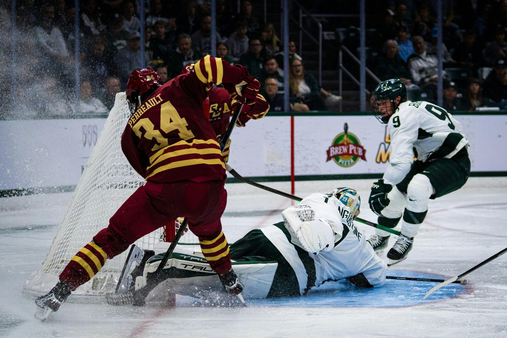 <p>Boston College sophomore forward Gabe Perreault (34) tries to muscle the puck into MSU's net during a match at Munn Ice Arena on Oct. 11, 2024. MSU sophomore goalie Trey Augustine (1) and junior defensman Matt Basgall (9) scramble to protect their net.</p>