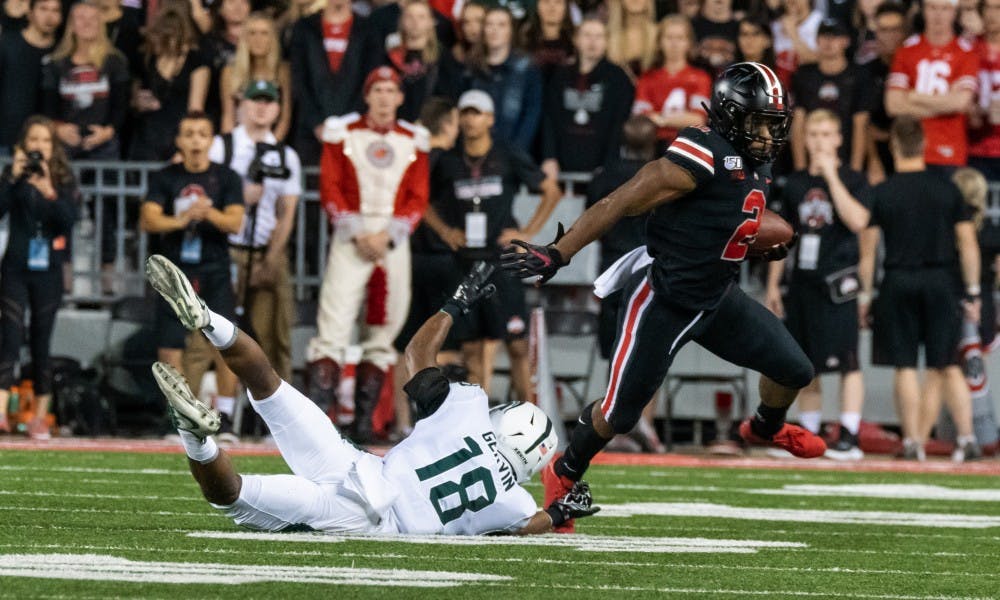 <p>Ohio state running back J.K. Dobbins (2) evades freshman cornerback Kalon Gervin (18). The Buckeyes defeated the Spartans, 34-10, at Ohio Stadium on Oct. 5, 2019. </p>