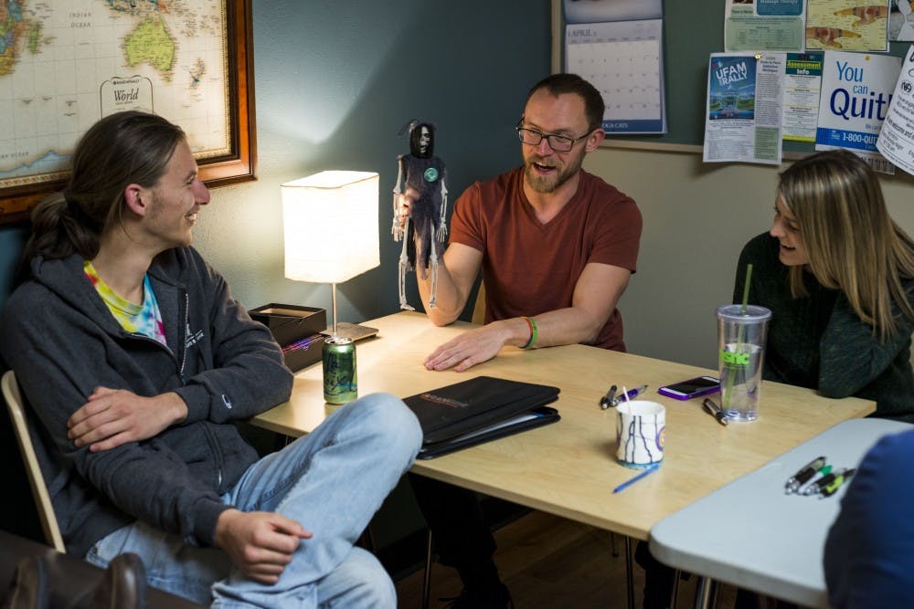 East Lansing resident Greg Dagner, center, holds up the skeleton he deemed the talking skeleton as he talks about his week during the MSU Traveler's Club meeting on March 31, 2017 at Olin Health Center. The MSU Traveler's Club is a club that provides a social space and support for people who are in recovery from addiction. 