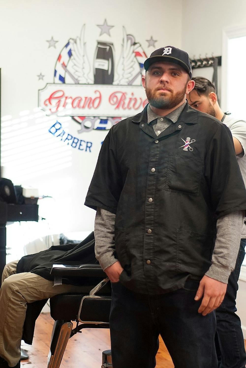 <p>East Lansing resident Grant Foley poses for a picture Feb. 23, 2015, at the Grand River Barber Company. Foley has been working as a barber for six years and loves what he does. Hannah Levy/The State News</p>