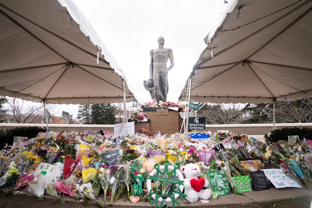 The Spartan Statue surrounded by bouquets of flowers and messages of support on Feb. 21, 2023. 