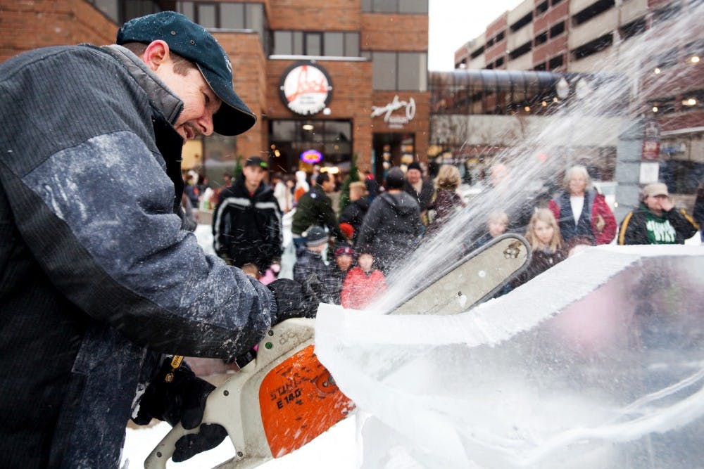 Lansing resident Scott Miller uses a chainsaw to carve away at a large block of ice Saturday afternoon at Winter Glow in downtown East Lansing. The event brought gave East Lansing residents the opportunity to get into the holiday spirit with food, performances, and carriage rides. Matt Hallowell/The State News