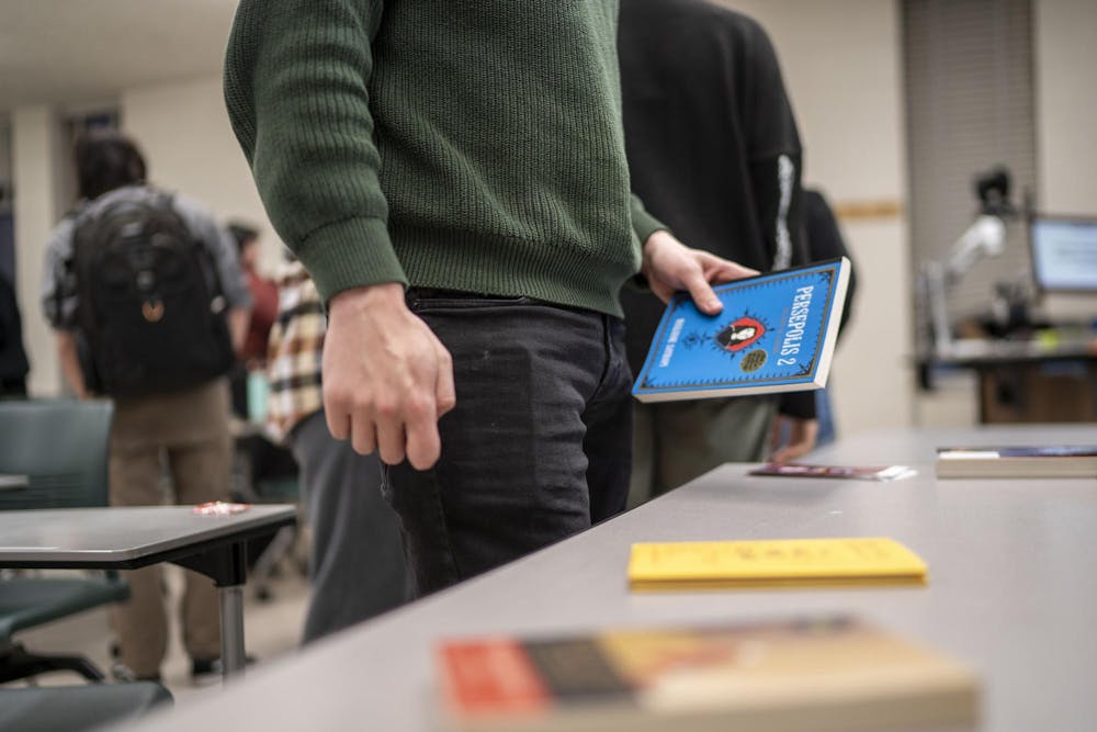 Psychology junior Myles Reeves holds a copy of "Persepolis 2" during Sigma Tau Delta's Banned Book Night at Wells Hall on April 21, 2025.