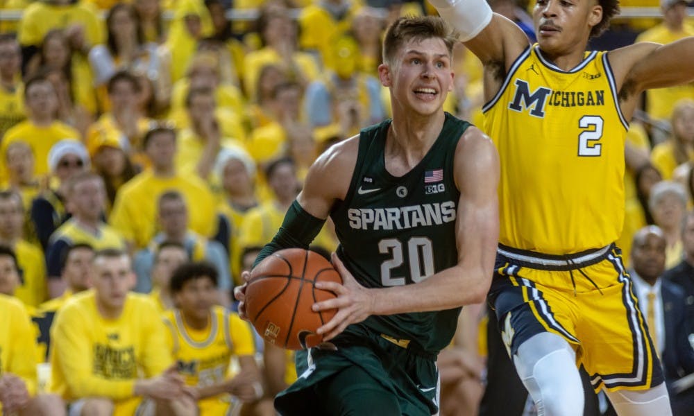 Senior guard Matt Mcquaid (20) drives on Michigan's Jordan Poole. The Spartans beat the Wolverines, 77-70, on Feb. 24, 2019 at the Crisler Center.