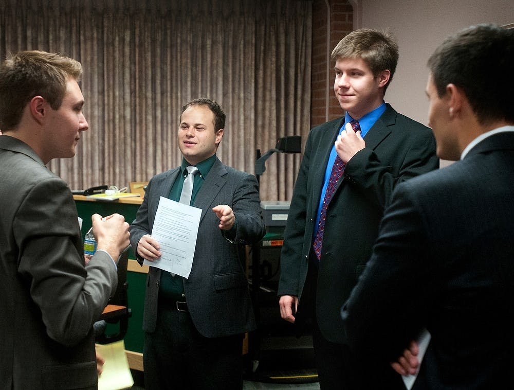 	<p>Political theory senior Stephen Wooden (right center), president of the Democratic Party on campus, adjusts his tie as international relations senior Will Hack (left center), debate moderator, decides which party will speak first at the campus debate on Thursday, Oct. 18, 2012. The Democratic, Republican, and Libertarian <span class="caps">MSU</span> campus parties were each represented at this debate. Katie Stiefel/State News </p>
