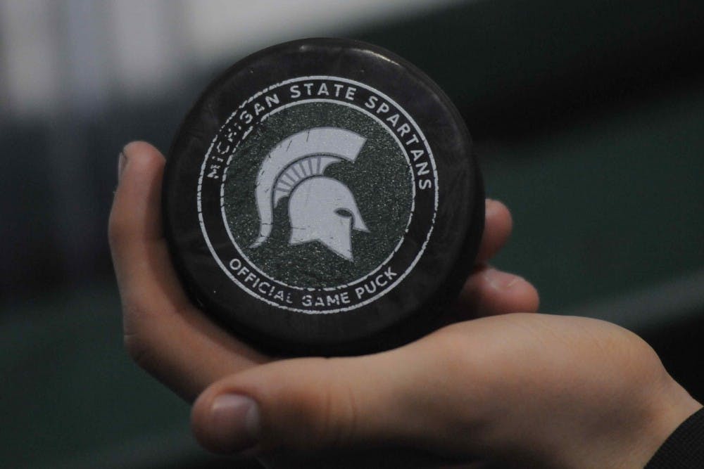 Cole Newman holds one of three pucks that went over the net during the game against Michigan on Feb. 9, 2018 at Munn Ice Arena. The Spartans and Wolverines tied 1-1, but the Spartans lost in a shootout. (Annie Barker | State News)