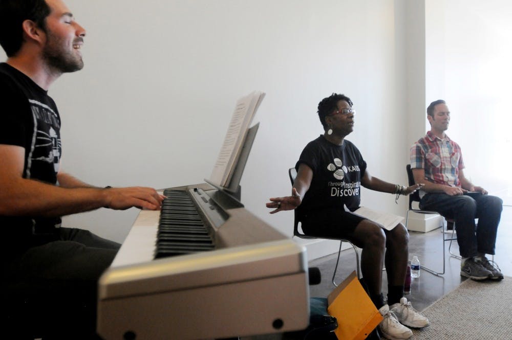 <p>Lansing resident Justin Reid plays the piano while Lansing residents Irene Unkefer and Jessie Still sing during a prayer circle Sept. 16, 2015 at The Furnace, 619 E. Grand River Ave., in East Lansing.</p>