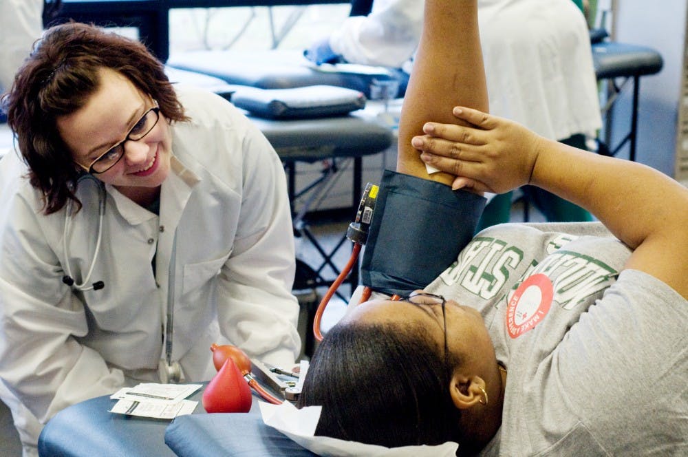 Red Cross employee Katie Emig helps social work senior Loren Johnson donate blood during the Alpha Phi Omega Blood Drive Challenge Tuesday at the International Center. Every year, MSU and U of M compete in the blood drive challenge sponsored by the Alpha Phi Omega National Service Fraternity.