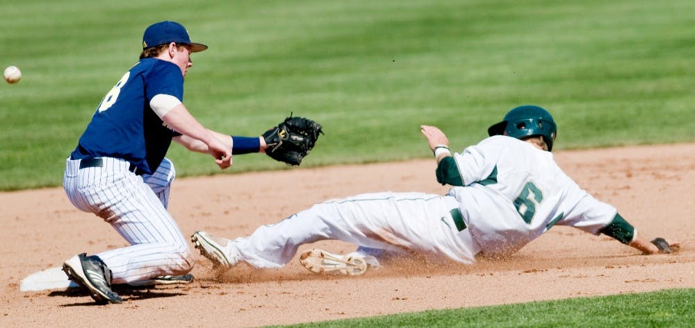 Junior outfielder Jordan Keur arrives the second base safe as Michigan infielder Dylan Delaney failed to catch the ball. The Spartans fell to the Wolverines on Saturday afternoon by 4-3 at McLane Baseball Stadium at Old College Field. Justin Wan/The State News