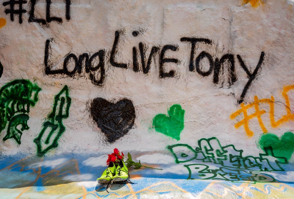 Flowers sit atop a pair of track spikes at the memorial for long jumper Tony Martin at the Rock on Farm Lane July 20, 2020. Martin died in a shooting in his hometown of Saginaw the morning of July 19. Martin held the high school state record for the long jump, with a jump of 26 feet and six inches.