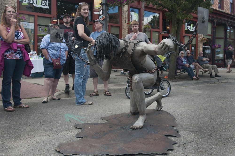 Festival attendees contemplate Jackson resident Kyle Orr's sculpture "Bezalels Art" at Scrapfest on July 16, 2016 in Lansing's Old Town.