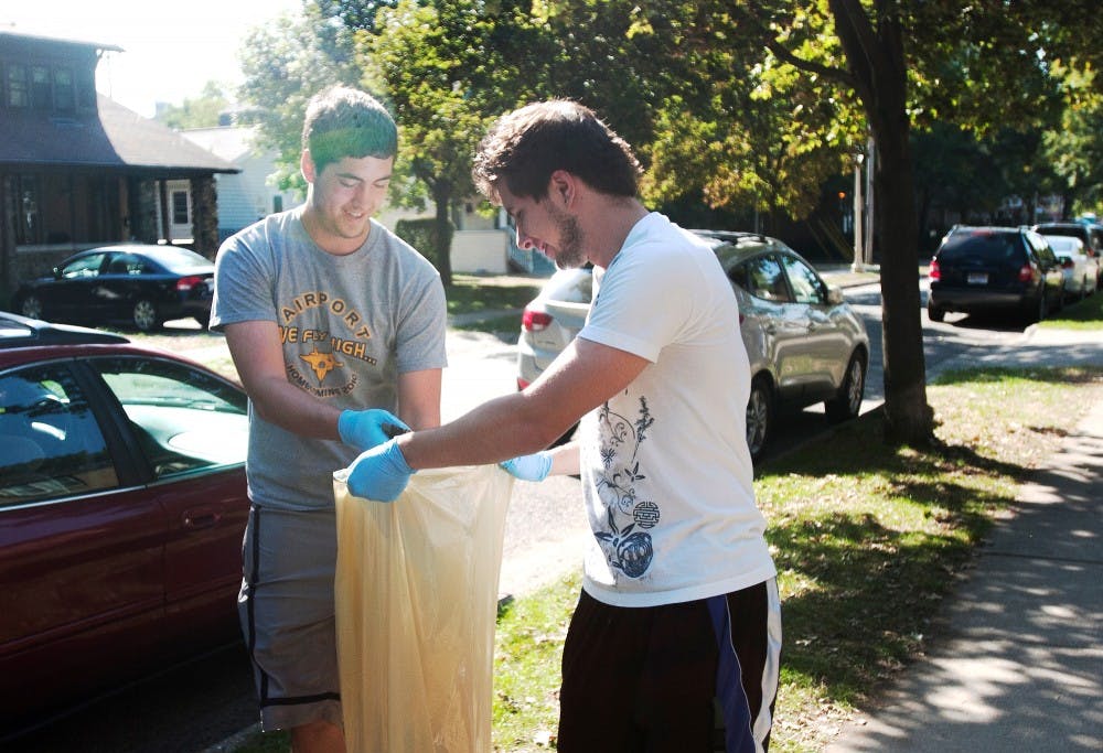 Freshman chemical engineering major Kyle Sims, left, and sophomore computer science major Scott Rucinksi help pick up the streets of East Lansing on the morning of Sunday, Sept. 16, 2012 after the Notre Dame football. The program was put together through the  University Student Commission to help clean up the local neighborhoods. James Ristau/The State News