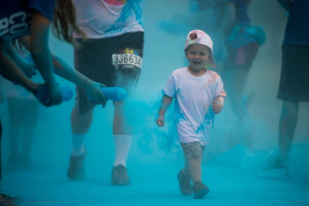 Lansing resident Jayce Venable, 2, runs through a color checkpoint during The Color Run Tropicolor World Tour on July 9, 2016 in Lansing, Mich. Venable was making his way through the third color checkpoint.