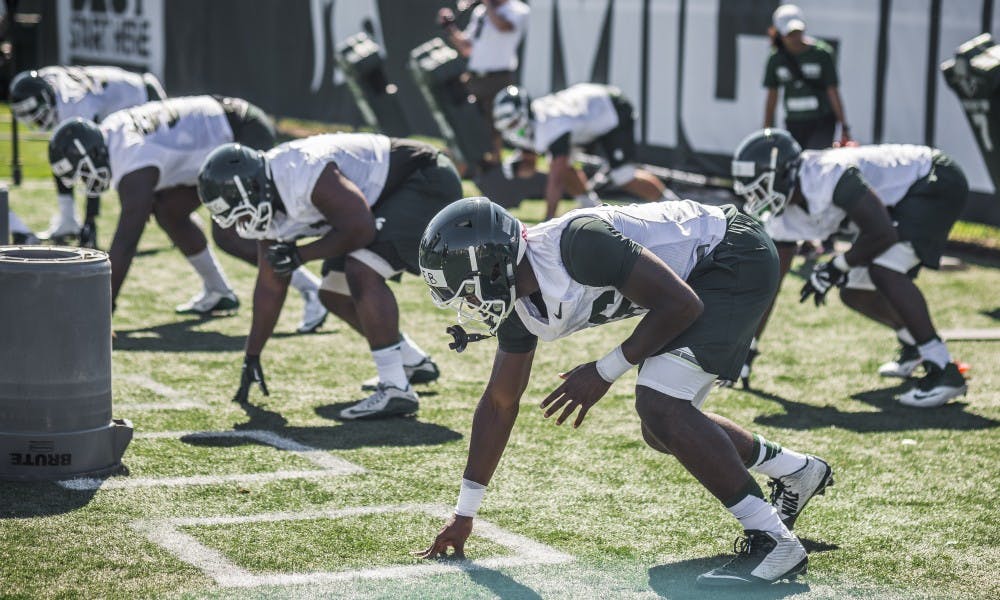 <p>Players line up to perform a defensive drill during the football practice on July 31, 2017, at the practice fields behind the Duffy Daugherty Football Building.</p>