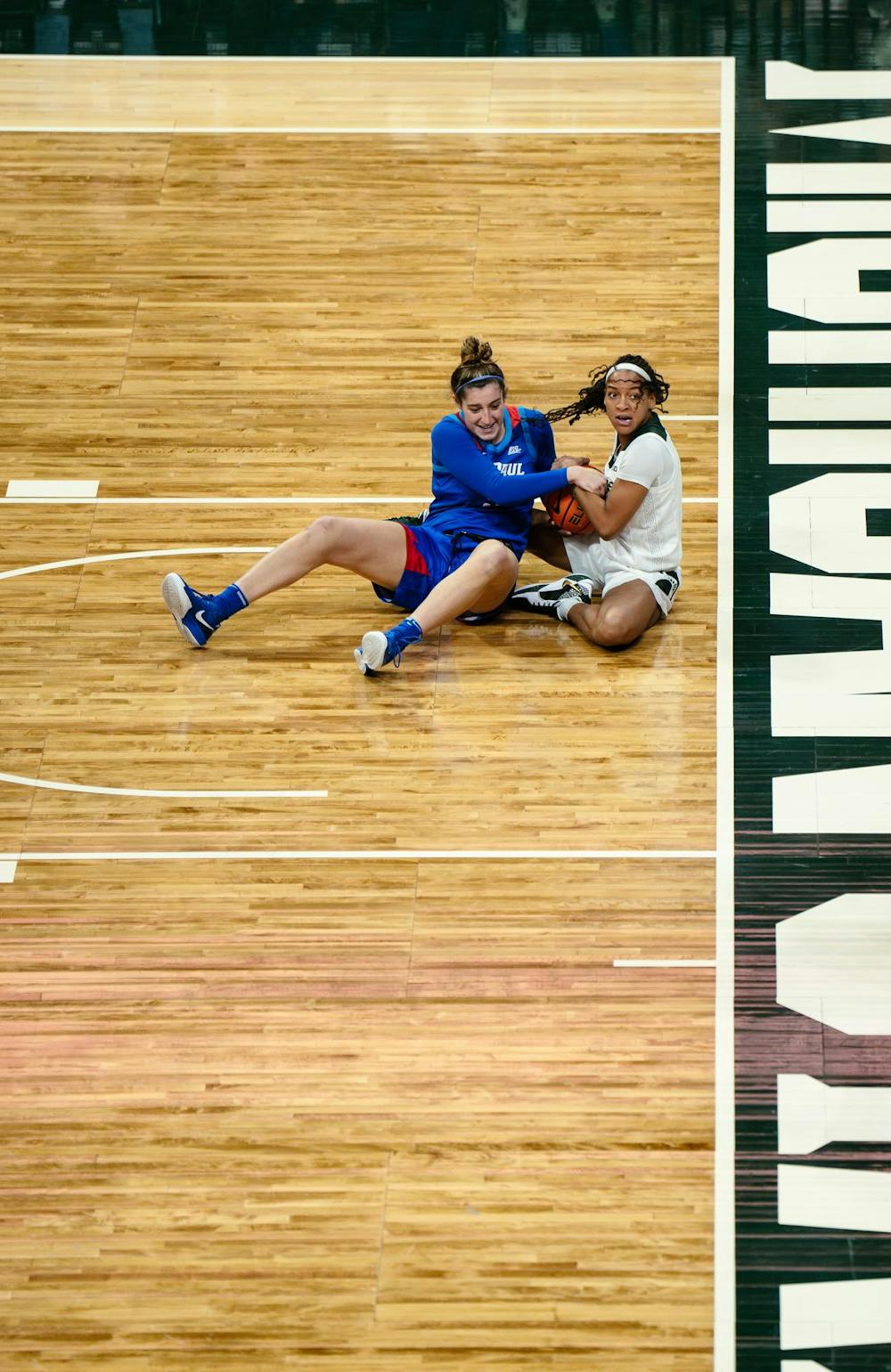 DePaul redshirt junior forward Meg Newman (9) and Michigan State senior guard/forward Jocelyn Tate (11) fight for the ball after falling to the ground at the Breslin Center on Dec. 8, 2024. The Spartans won 89-61 against the Blue Demons, starting the season 9-0 for the first time in program history. 