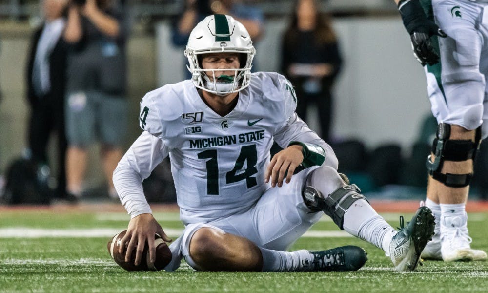 <p>Senior quarterback Brian Lewerke (14) sits on the field after being sacked by the Ohio State defense. The Buckeyes defeated the Spartans, 34-10, on Oct. 5, 2019 at Ohio Stadium.</p>