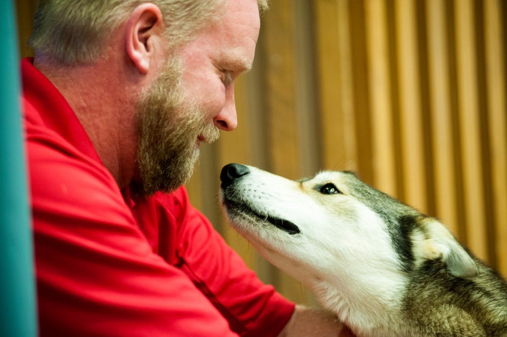 McMillan resident Ed Stielstra pets his dog, Enzo on April 15, 2016 at Erickson Hall Kiva. Stielstra graduated from Lyman Briggs School in 1993.