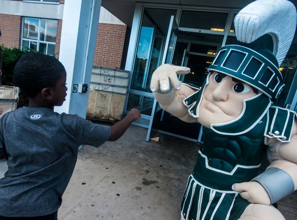 Detroit resident Ronald Coleman, 5, poses for a photo with Sparty on Aug. 28, 2016 at West Akers Hall. Coleman was helping his cousin move in to his dorm room. 