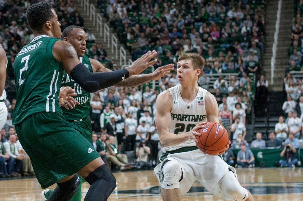 Freshman guard Matt McQuaid drives the ball to the net for a layup as Eastern Michigan center James Thompson IV, 2, and Eastern Michigan guard Willie Mangum IV, 10, defend during the first half of the game against Eastern Michigan on Nov. 23, 2015 at Breslin Center. The Spartans defeated the Eagles, 89-65.