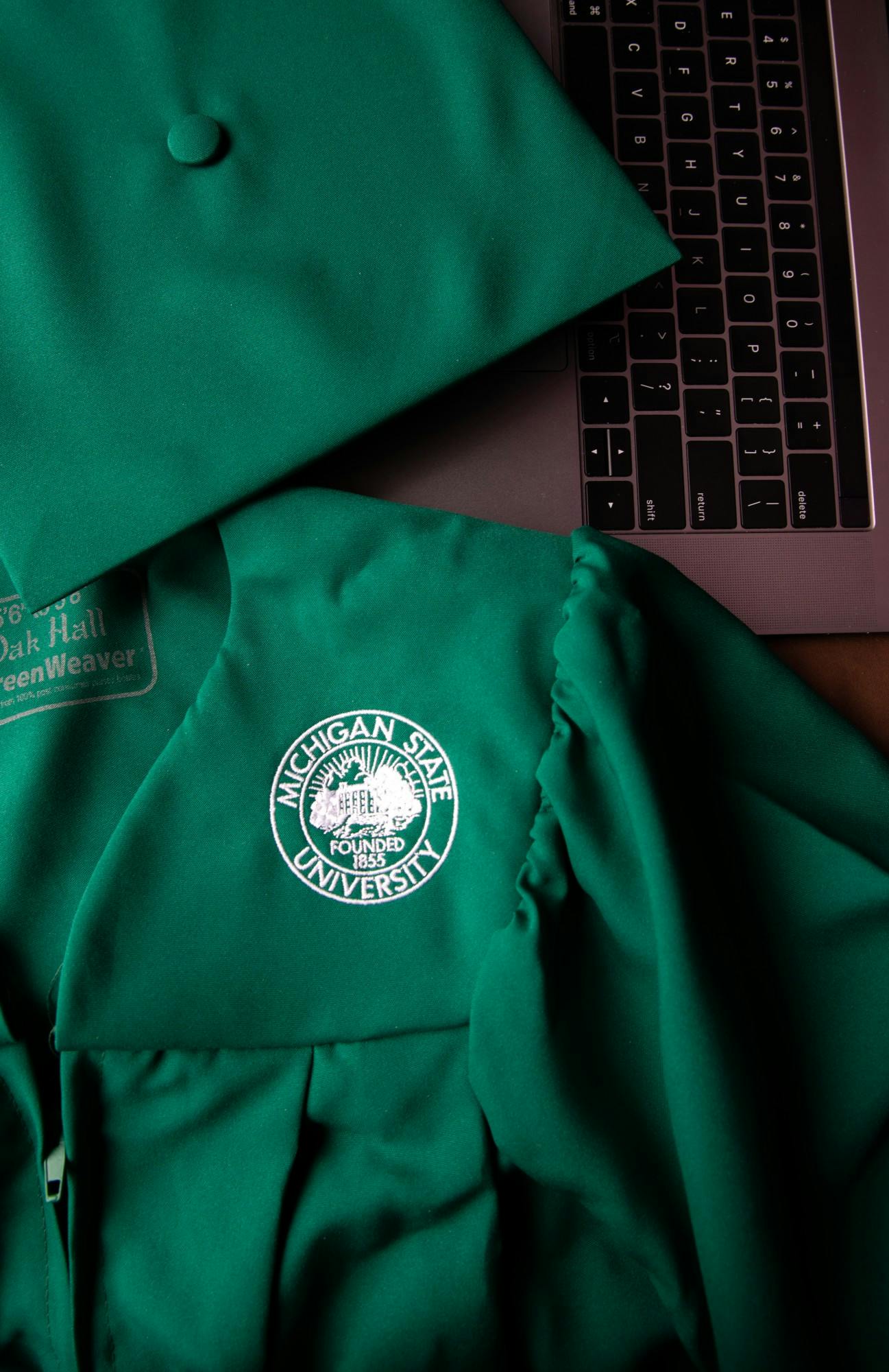 <p>A graduation cap and gown photographed next to a laptop on April 22, 2020.</p>