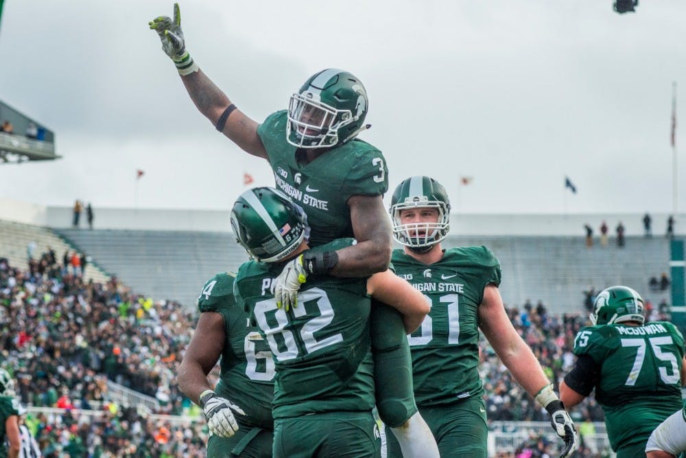 <p>Sophomore running back L.J Scott (3) is picked up by senior tight end Josiah Price (82) after scoring a touchdown during the game against Ohio State on Nov. 19, 2016 at Spartan Stadium. The Spartans were defeated by the Buckeyes, 17-16.</p>