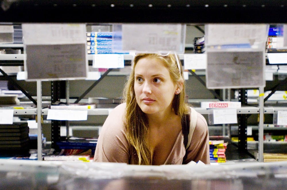 <p>Spanish senior Shannon McNeilly looks for her linguistics and languages textbooks inside Ned’s Book Store, 135 E. Grand River Ave., on Aug. 30, 2011.&nbsp;</p>