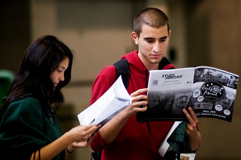 Premedical sophomore Issam Beydoun, right, and human resource management sophomore Alex Berekke take a look at the Study Abroad Fair Guide Wednesday at the Breslin Center. The fair featured booths and information on most of the 275 study abroad programs MSU offers. Matt Radick/The State News