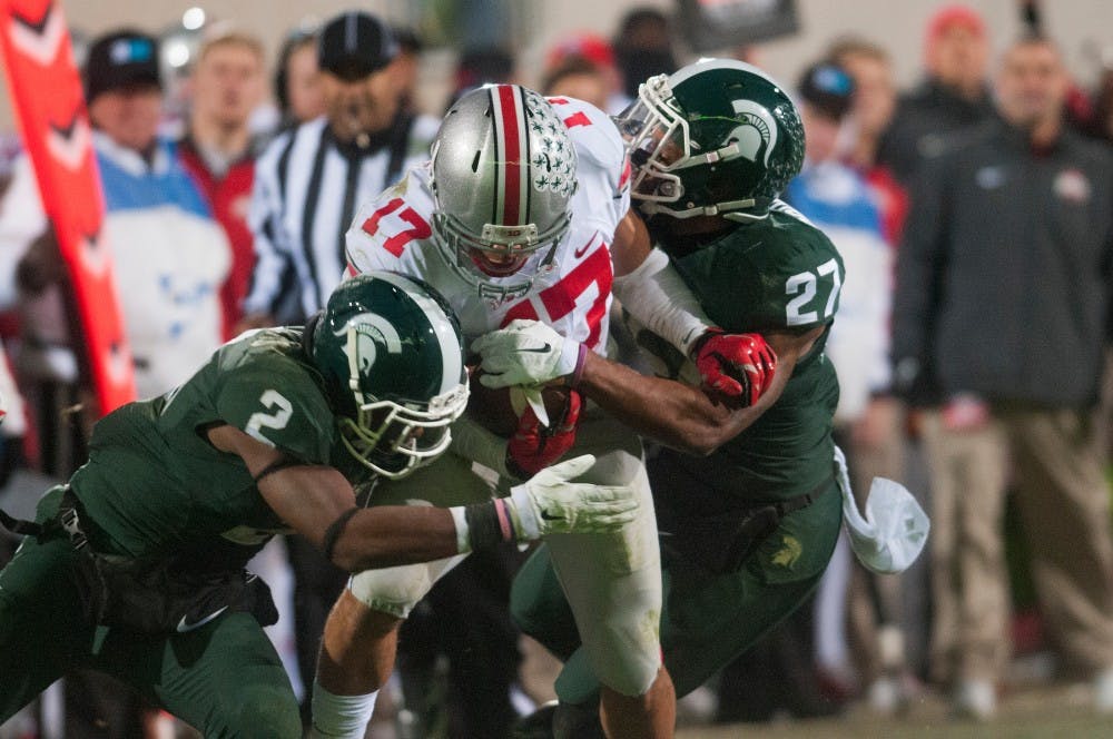 <p>Sophomore corner back Darian Hicks and senior safety Kurtis Drummond tackle Ohio State half back Jalin Marshall during the game against Ohio State on Nov. 8, 2014 at Spartan Stadium. The Spartans were defeated by the Buckeyes, 49-37. Jessalyn Tamez/The State News </p>