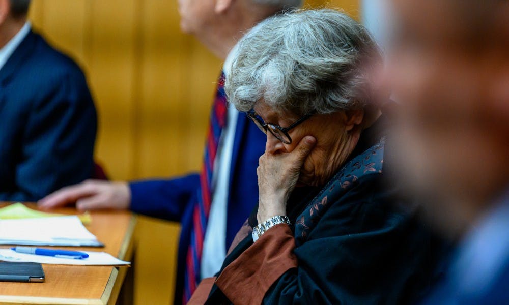 <p>Former MSU President Lou Anna K. Simon (center) holds her face during the continuation of her preliminary exam July 12, 2019.</p>