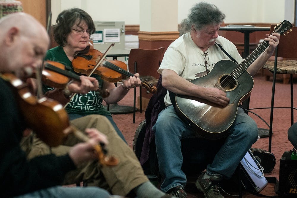 <p>Bath resident Mary Ross and Community Music School instructor John Hatton play violin and guitar March 17, 2017 in the folk group that jams in Snyder hall. The group includes students, professors, and people from around the area who play different instruments and gather to play folk music. Allyson Telgenhof/The State News.</p>