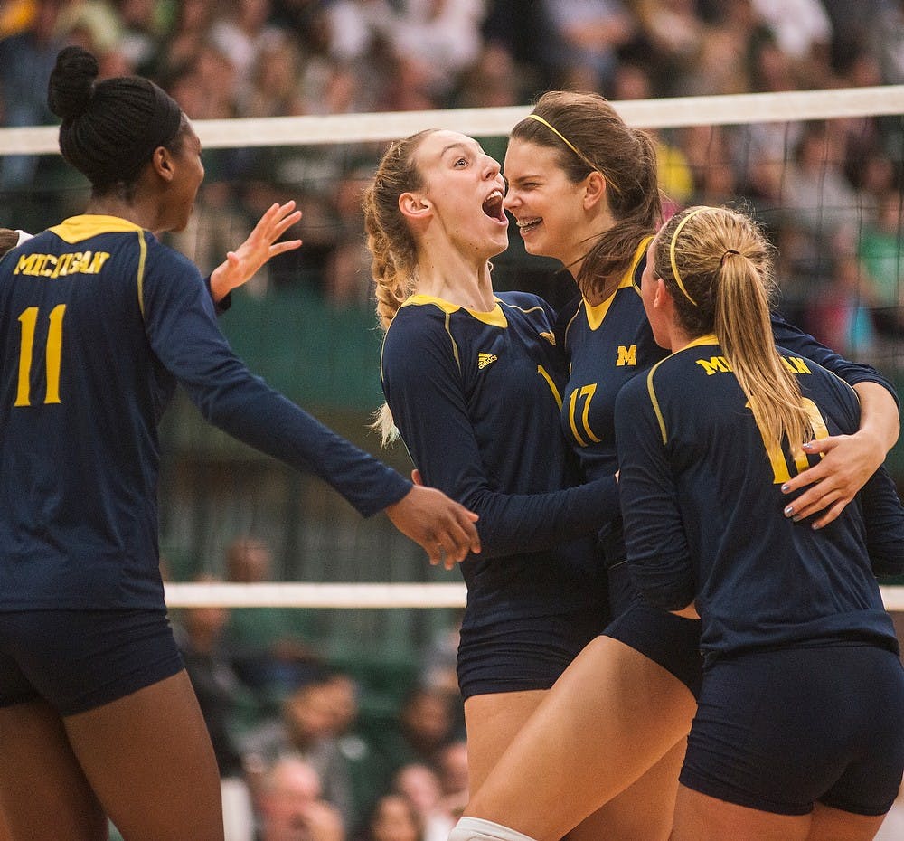 <p>From left, Michigan outside hitter Adeja Lambert, middle blocker Claire Kieffer-Wright, middle blocker Abby Cole, and setter Lexi Dannemiller cheer after a point Oct. 3, 2014, during a game against the University of Michigan at Jenison Fieldhouse. The Spartans defeated the Wolverines, 3-1. Erin Hampton/The State News</p>