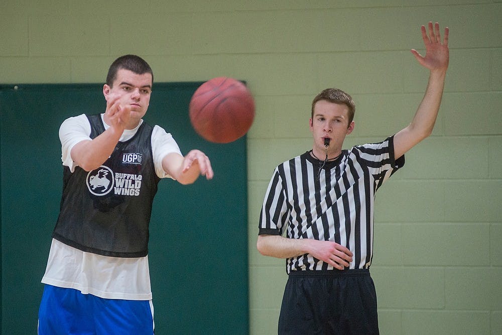 <p>Accounting freshman Kevin Wenner passes the ball as social studies education senior Chad Stevens starts the clock on Mar. 18, 2015, while working as an IM official supervisor during an intramural basketball game at IM Sports East. Stevens has been a referee for IM Sports for 3 years and referees for basketball games at IM Sports facilities at least 3 nights a week. Emily Nagle/The State News</p>