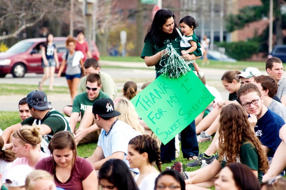 MSU alumna Heena Patel and Aanya Patel, 1 year, wait with the crowd to send off the Spartan basketball team on their bus Monday outside Breslin Center. The Spartans reached the Sweet 16 and will play No. 4 seed Louisville on Thursday night in the regional semifinals in Phoenix. Derek Berggren/The State News