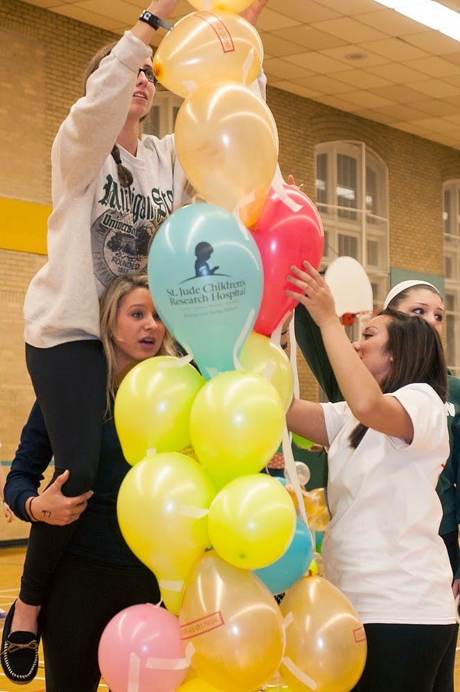 	<p>Pre-medical freshman Jaqui Somes sits on the shoulders of supply chain management freshman Jamie Ulanch while while building a balloon tower with teammates Nov. 15, 2013, at IM Sports-Circle. Students stayed up all night playing games, watching videos and eating to celebrate their fundraising for St. Judes research hospital.</p>