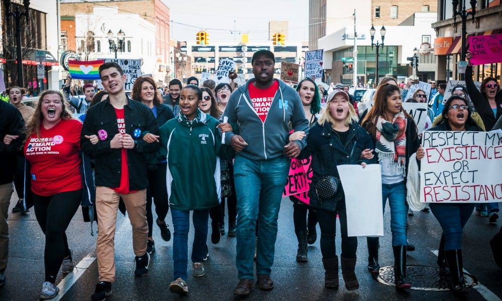 Protesters march through the intersection of  Allegan street and Washington square on Jan. 21, 2017 near the Capital Building in Lansing. Activists gathered and expressed their opinions.