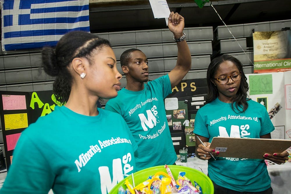 <p>From left, human biology junior Michella McCormick, human biology junior Kyle Bivins and neuroscience junior Michelle Aguwa pass out flyers for Spartan MAPS, Minority Association of Pre-Medical Students, on Sept. 14, 2014, during Sparticipation at Breslin Center. Erin Hampton/The State News</p>