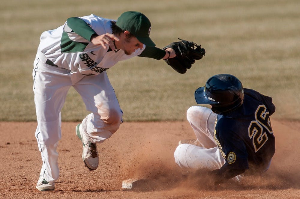 	<p>Michigan center fielder Patrick Biondi reaches second base before sophomore shortstop Ryan Richardson could tag him out, Friday, April 5, 2013, at McLane Stadium at Old College Field. The Spartans fell to the Wolverines in the first of the three-game series, 6-3. Justin Wan/The State News</p>