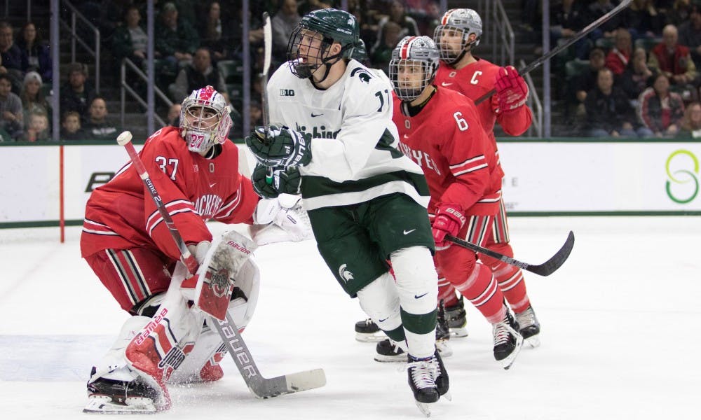 Sophomore center Tommy Apap (11) watches the puck in front of Ohio State goaltender Tommy Nappier (37) during the game against Ohio State University at Munn Ice Arena on Jan. 5, 2019. The Spartans fell to the Buckeyes, 6-0.