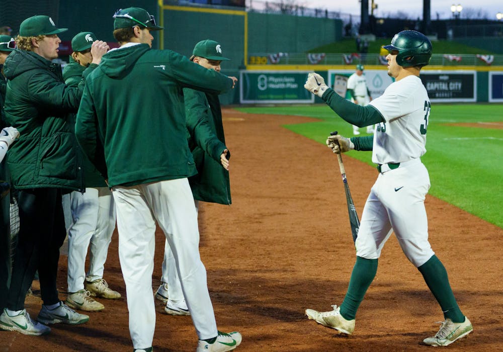<p>Michigan State junior left fielder Casey Mayes (33) fist bumps his team after scoring another run for Michigan State in the bottom of the ninth. Michigan State lost 18-6 to Michigan on April 15, 2022 at the Lugnut Stadium.</p>