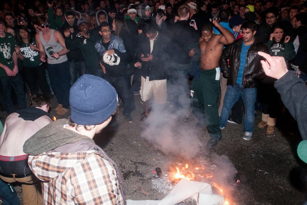 	<p>Participants huddle around a small fire in the streets of Cedar Village after an <span class="caps">MSU</span> victory in the Big Ten Championship game on Dec. 8, 2013. The police and fire department responded to multiple fires across East Lansing.</p>