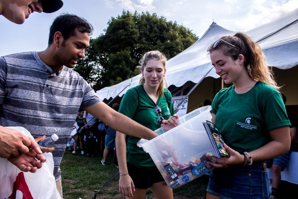 Physiology senior Mayank Jayaram grabs candy from professional writing senior Alexia Kienitz during Sparticipation on August 28, 2018 at Cherry Lane Field. Thousands of students attended the annual event which gives student organizations the chance to recruit new members.