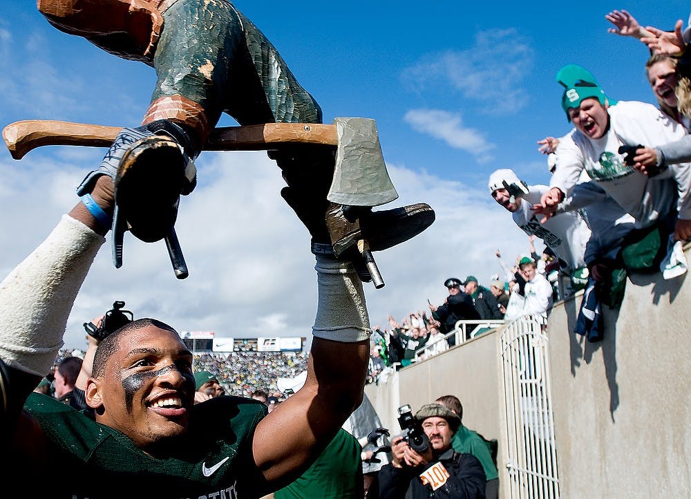 <p>Senior linebacker Brandon Denson holds up the Paul Bunyan Trophy after the Spartans defeated the University of Michigan in overtime 26-20 on Oct. 3, 2009, at Spartan Stadium. Josh Radtke/The State News</p>