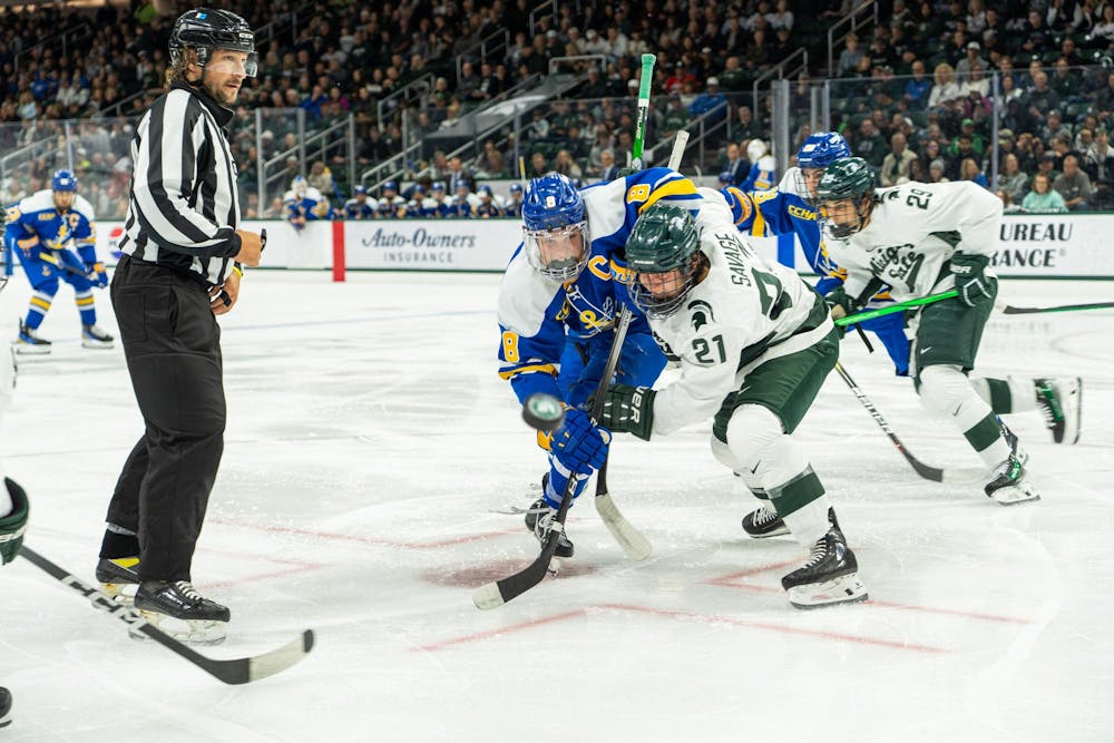 <p>LSSU captain Harrison Roy and MSU forward Red Savage battle for a flying puck at Munn Ice Arena on Saturday, Oct. 7, 2023. Both skaters recorded one goal in the matchup. The Spartans won 5-2.</p>