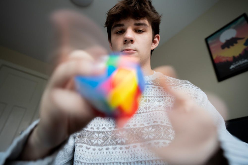 <p>Colors blur as experience architecture senior Owen Widdis, 22, scrambles his Rubik’s cube in his home in East Lansing on Sunday, Feb. 18, 2024. Widdis reckons he can scramble the cube at 13 or 14 turns per second, or TPS, creating a blurred rainbow.</p>